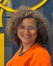 Professionelles Porträt der ViaNova-Gründerin Sandra Santos, mit Brille und orangefarbenem Oberteil, lächelnd.